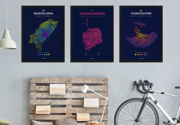 Three posters, made by Vélographs, hanging on the wall, showing the reachable area by bike of three different cities.